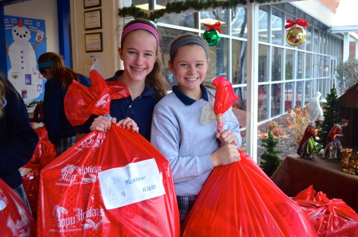 St. Ann students Jacqueline (L) and Ellie Platt load bags of gifts at the school Friday afternoon.