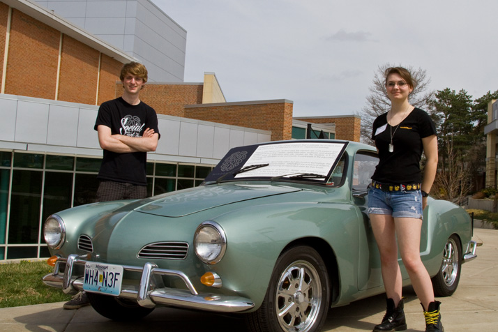 SM East senior Anastasia Tevis and junior Andrew Treas stand next to one of the Volkswagen Karmann Ghias restored through the Minddrive program to run on electricity. Tevis will be one of the drivers who takes a Ghia down the California coast next month.