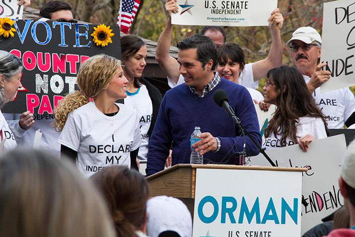 Greg Orman and his wife, Sybil, were flanked by supporters waving signs as he made his remarks in Prairie Village Sunday.
