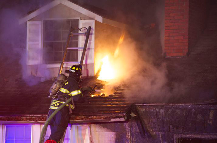 Firefighters doused flames that erupted from the roof after they vented it with axes and saws. Photo by Daniel Blom.