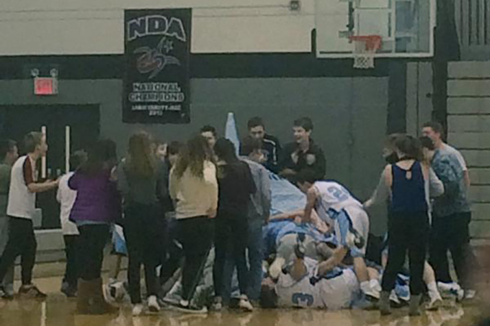 SM East players piled on the court after Joseph Brouillette's half court shot gave them a last-second win over rival SM South. Photo via SME Cheer Twitter.