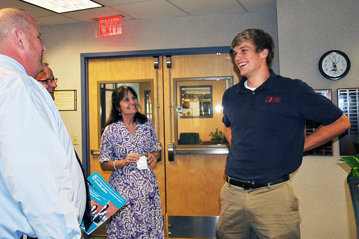 Bishop Miege administrator Randy Salisbury, president Dr. Joe Passantino, and guidance counselor Elaine Schmidtberger delivered the news to Nolan Gray that he was a National Merit Semifinalist. Photo via Bishop Miege Facebook.