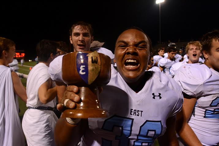 Senior Calen Gilmore carries the Nut Cup to the locker room after a 42-21 victory. Photo by Joseph Cline
