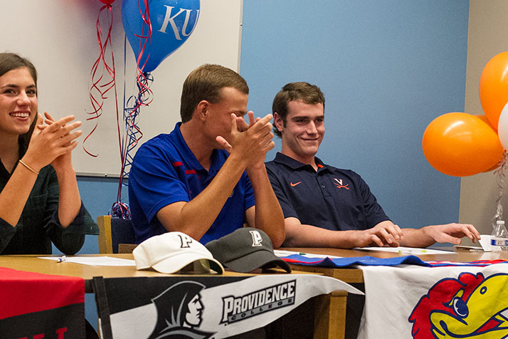 Joey Wentz grins at the crowd applauds him following Coach Jerrod Ryherd's remarks in the SM East library Wednesday.