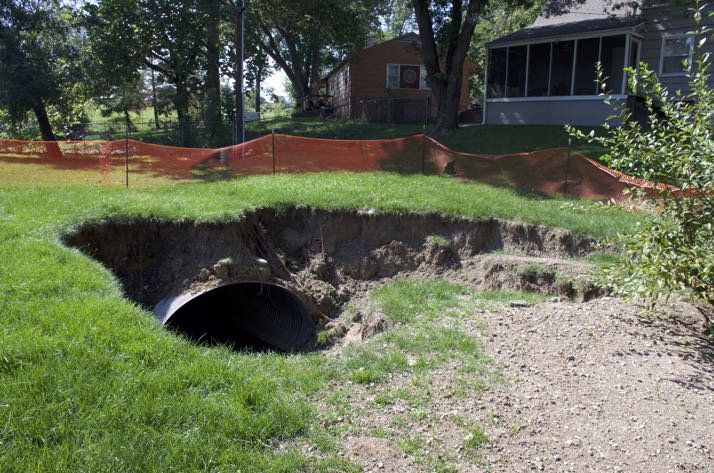 A large hole opened behind several Mission houses after metal pipe failed.