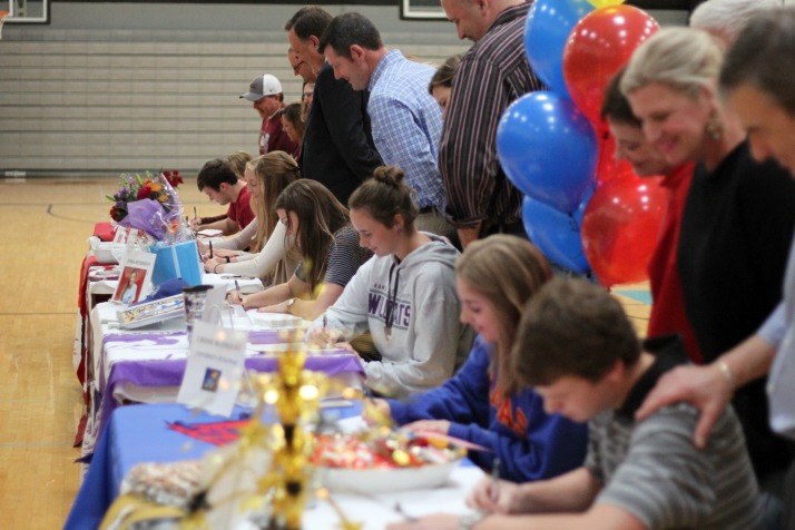 With their parents looking over their shoulder, eight Shawnee Mission East seniors sign their ceremonial National Letter of Intent. The real NLIs were faxed into the schools on Wednesday morning.