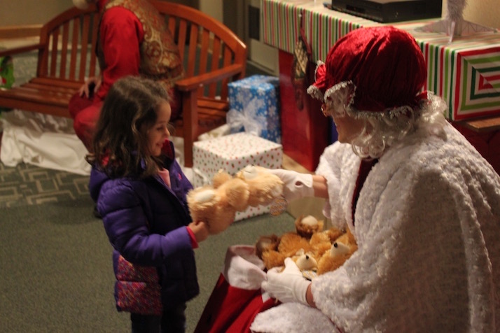 Mrs. Claus hands out a Teddy Bear.