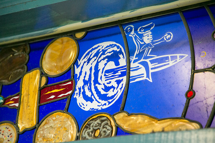 The shop's logo, featuring a pastry chef riding a rocket through the center of a donut, is a familiar sight on the shop's donut boxes and in a stained glass display above the front door.