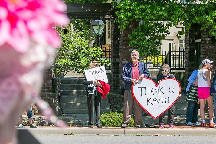 A couple held up a sign thanking Yoder for his vote across the street from people protesting the same.