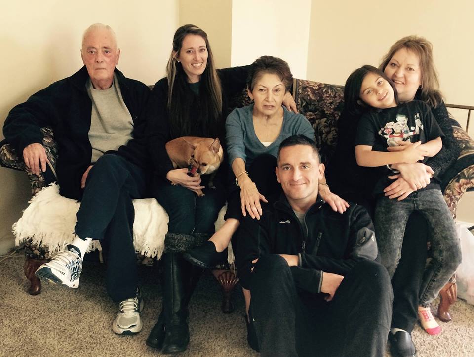Santos Thompson, seated on the ground, with his family. Photo via Facebook.